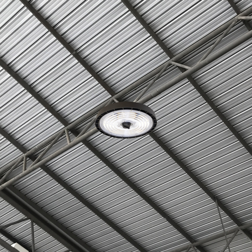 Integral LED Perform Pro Max Circular High Bay luminaire installed on a metal support strut against a corrugated metal ceiling